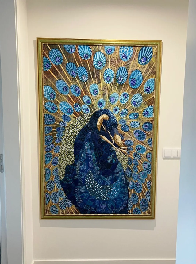 Detailed peacock painting with blue feathers and gold rays in a frame.